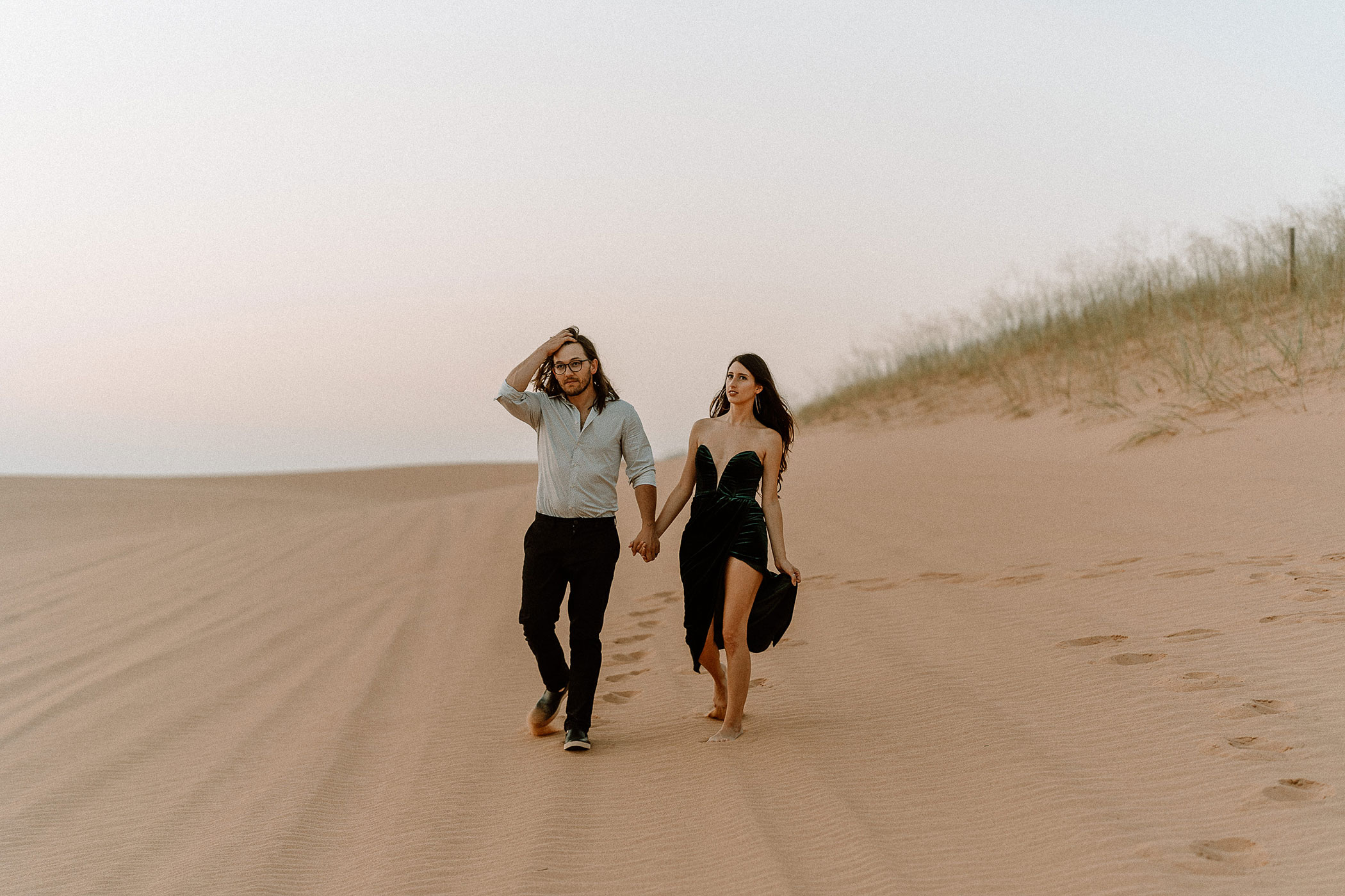 Engaged couple walking in the sand dunes in Little Sahara Park in Oklahoma, photographed by Hannah Hix