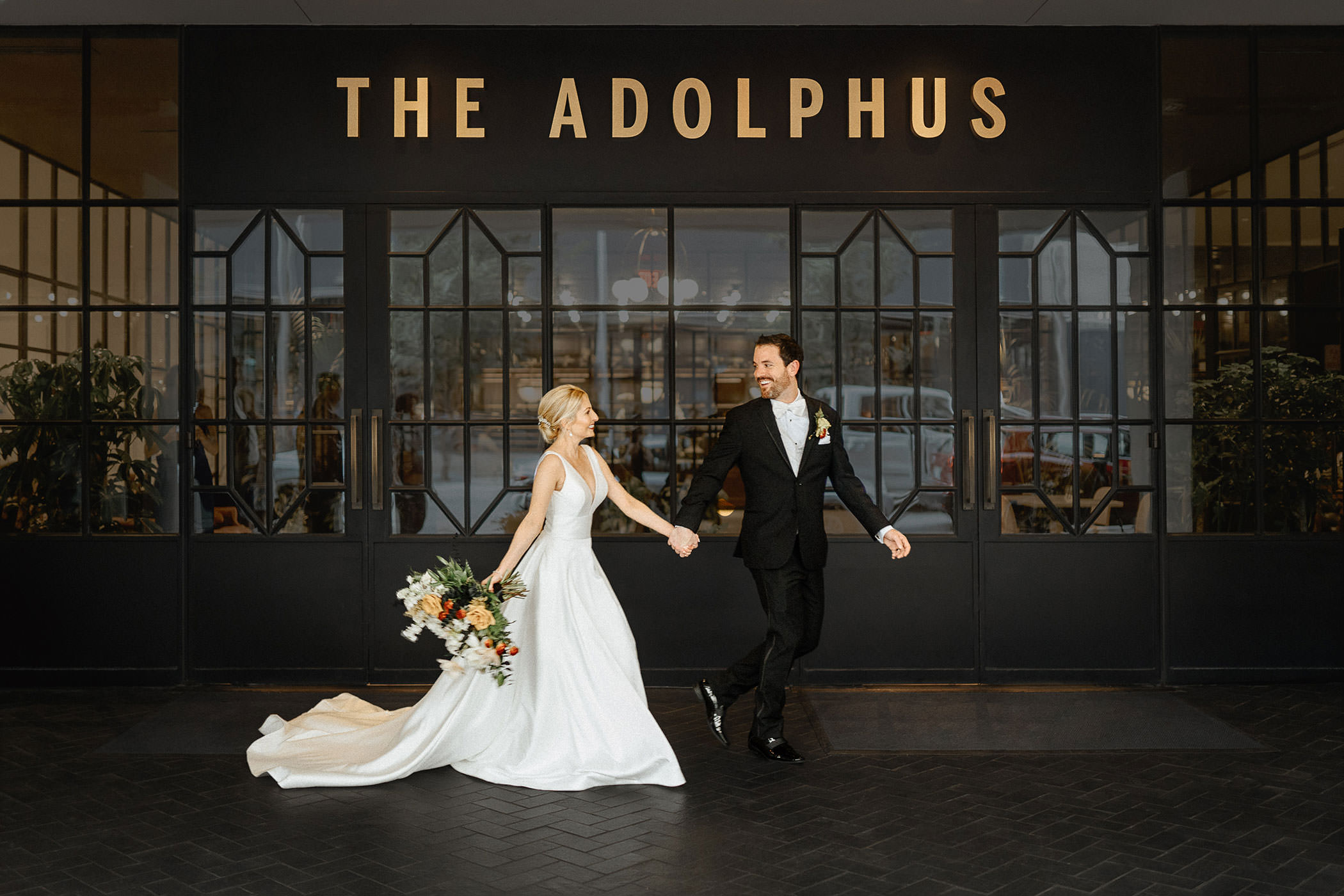 Couple running in front of hotel sign, Dallas wedding at the Adolphus Hotel photographed by Hannah Hix