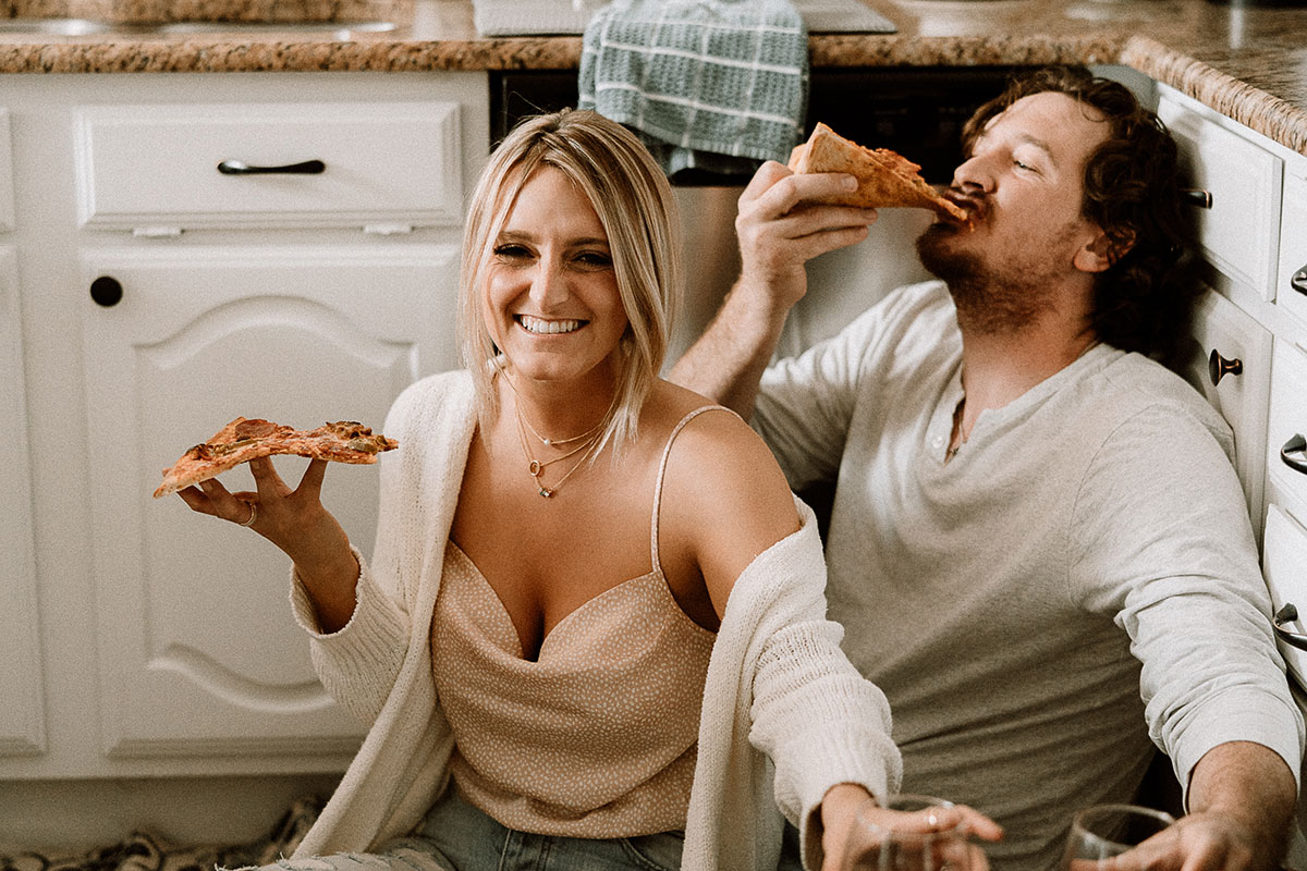 Engaged couple having fun, eating pizza for an in-home lifestyle engagement session, photographed by Hannah Hix, Dallas Wedding Photographer