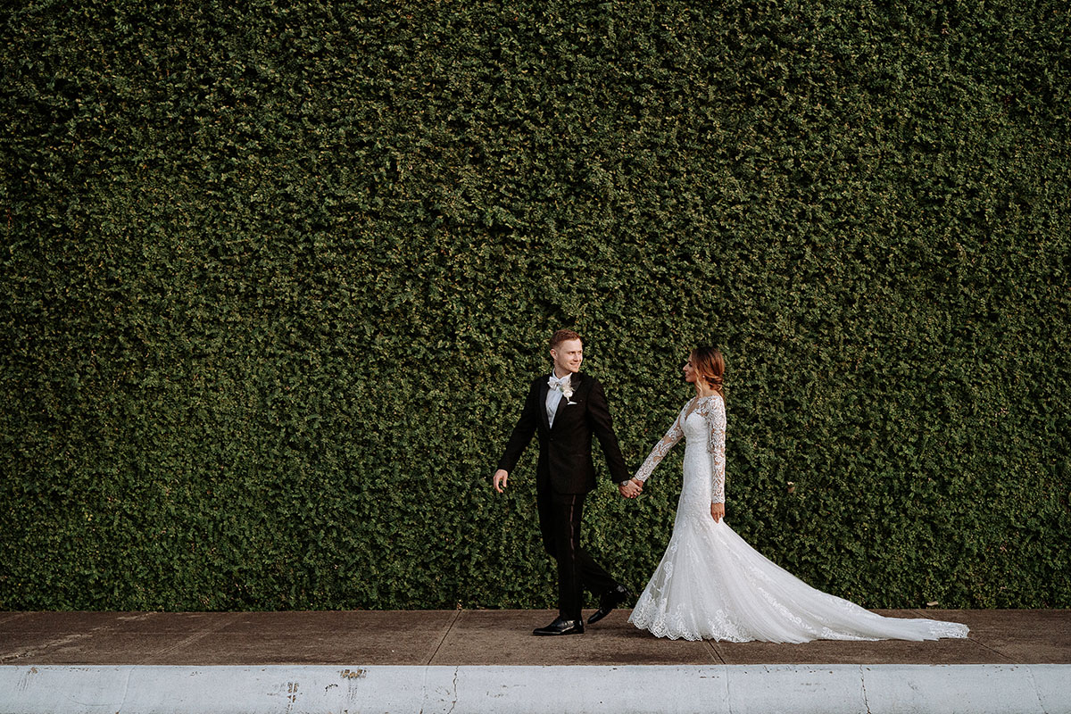 Wedding couple walking by a living green wall by Howell and Dragon in Dallas, photographed by Hannah Hix
