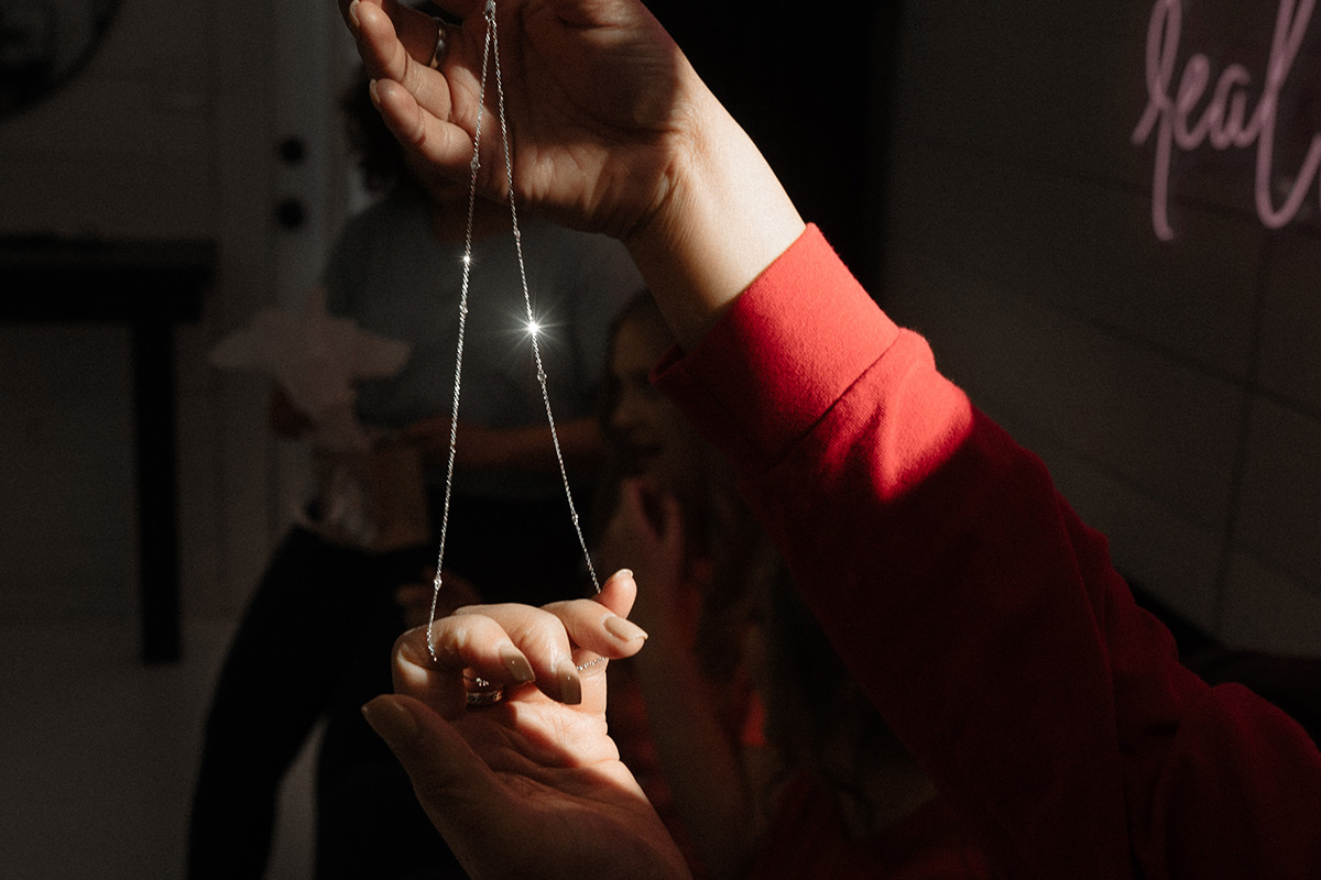women holding a necklace and light sparkles off of it