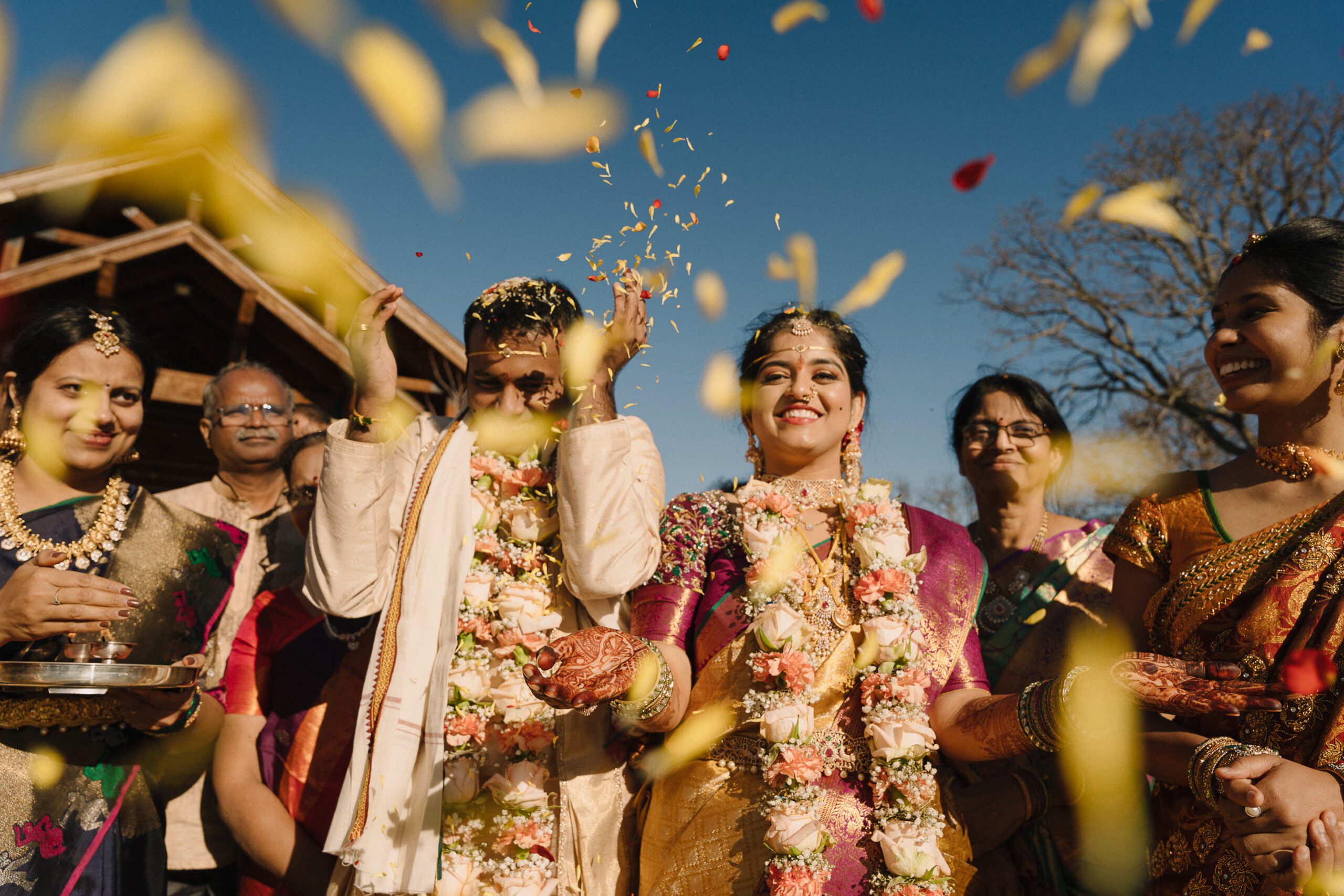 South Indian bride and groom on their wedding day throwing flower petals