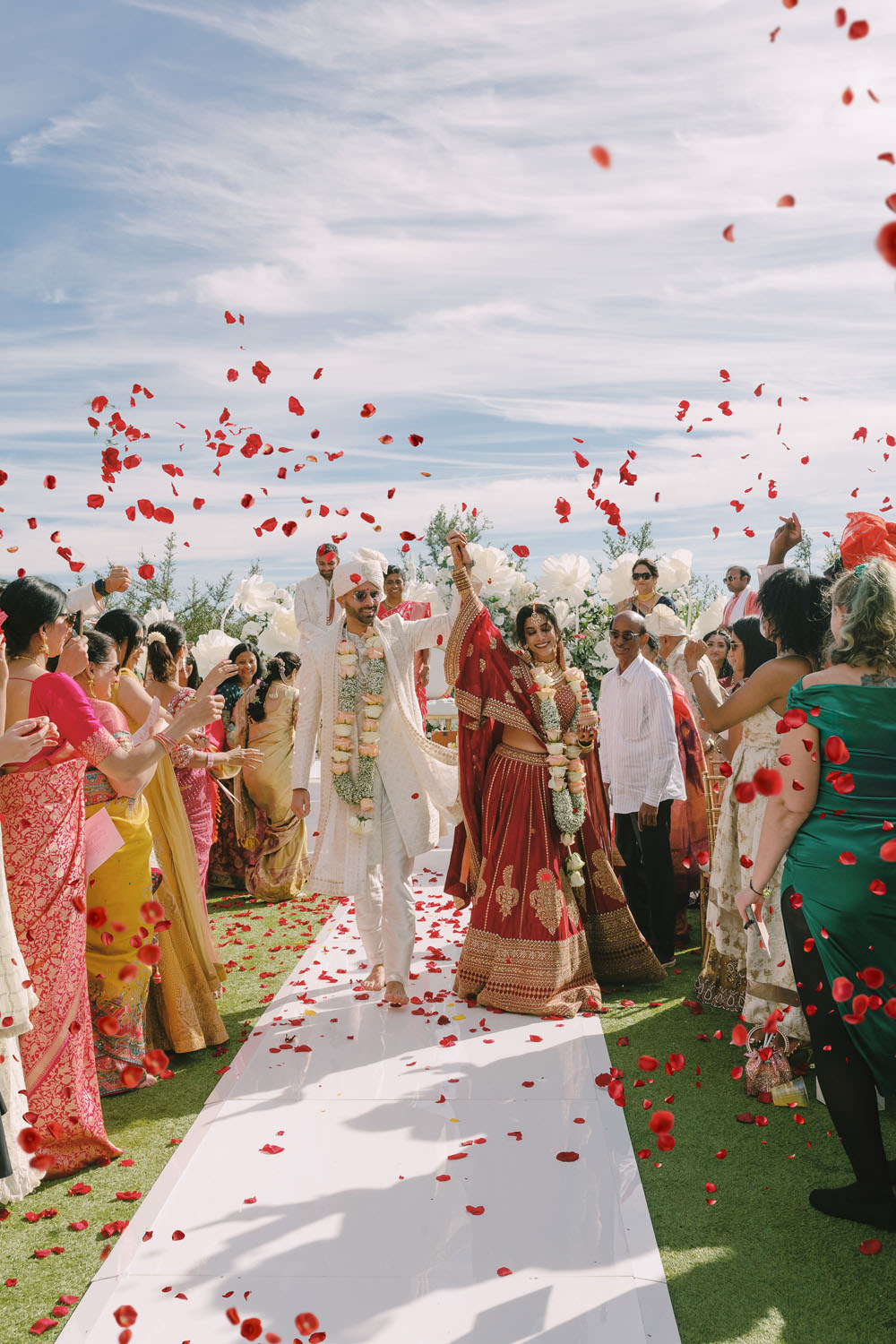Indian bride & groom walking through a shower of rose petals during their wedding ceremony on a bright, sunny fall day in Dallas, Texas at the Omni PGA