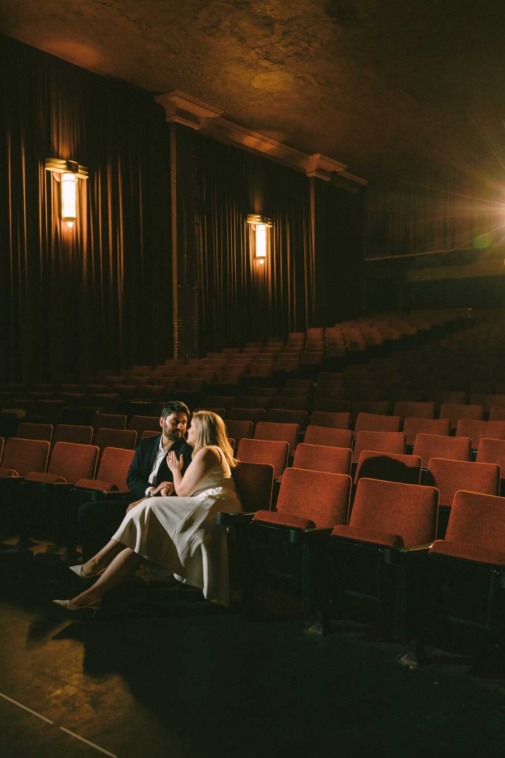 Engaged couple sitting together under the glow of theater lights at SIFF Cinema, Seattle engagement photographer