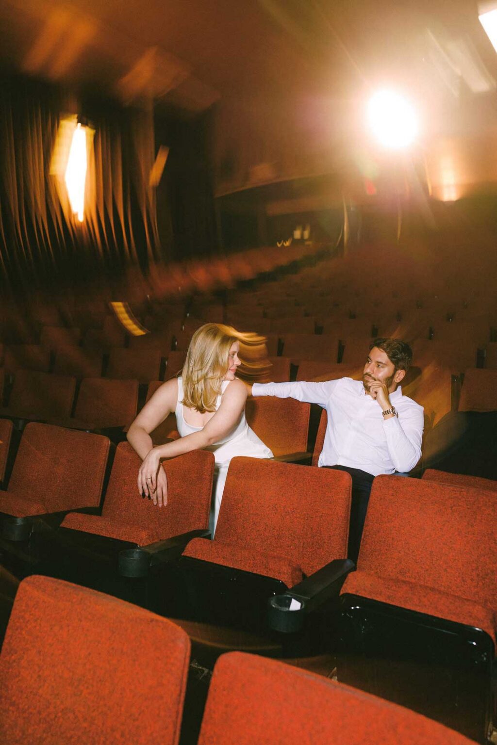 Engaged couple sharing a quiet moment in the velvet seats of SIFF Cinema in Seattle, moody cinematic engagement photo