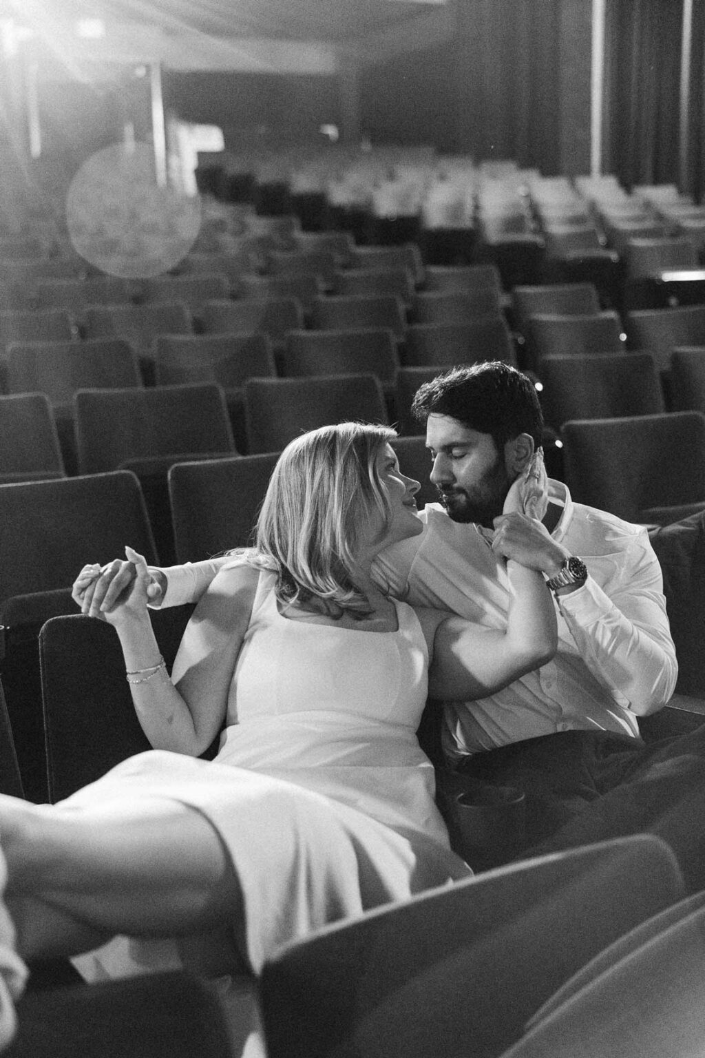 Black and white intimate portrait of two people in a dimly lit movie theater, moody engagement photography Seattle