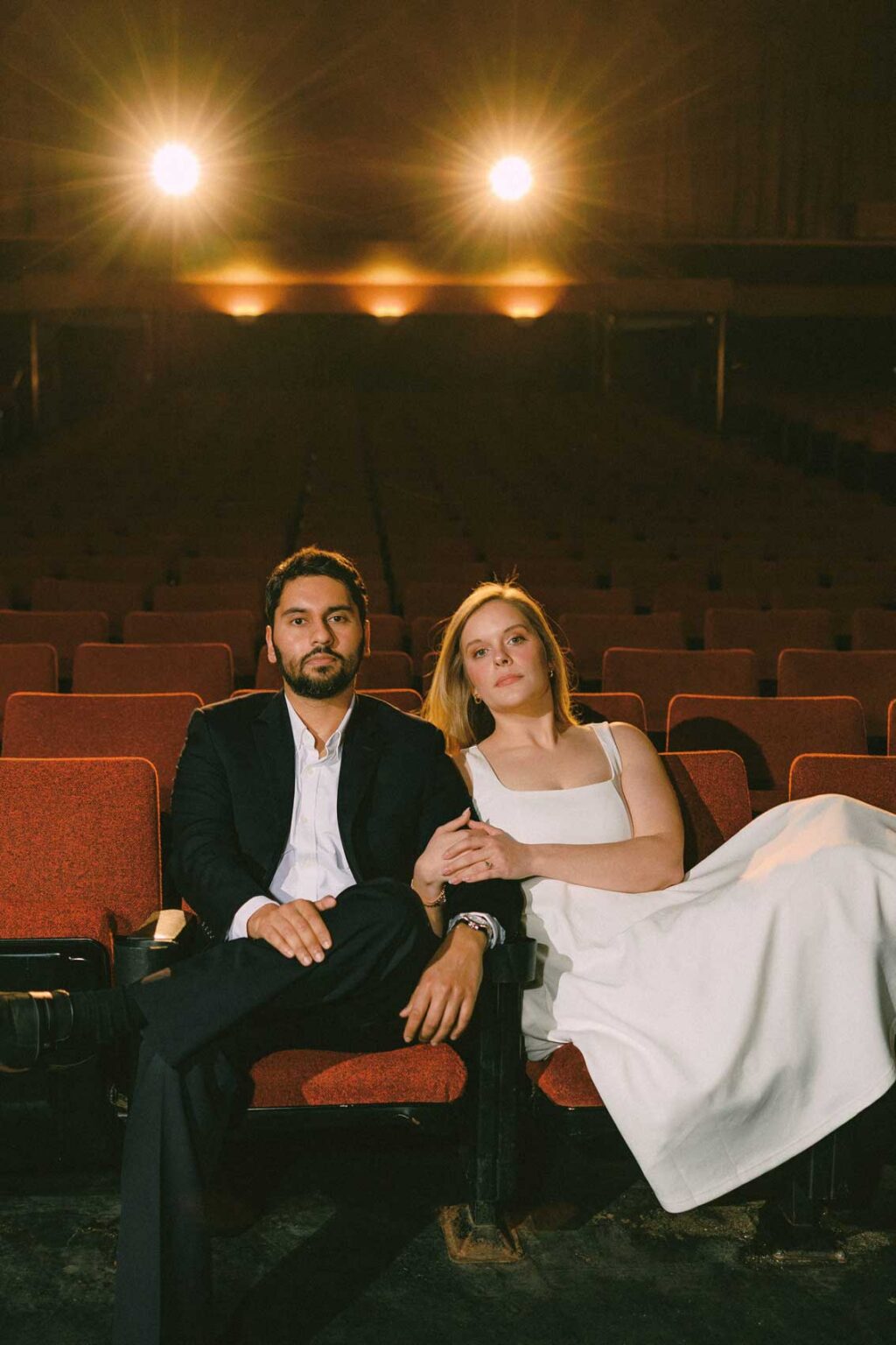 Engaged couple sharing a quiet moment in the velvet seats of SIFF Cinema in Seattle, moody cinematic engagement photo