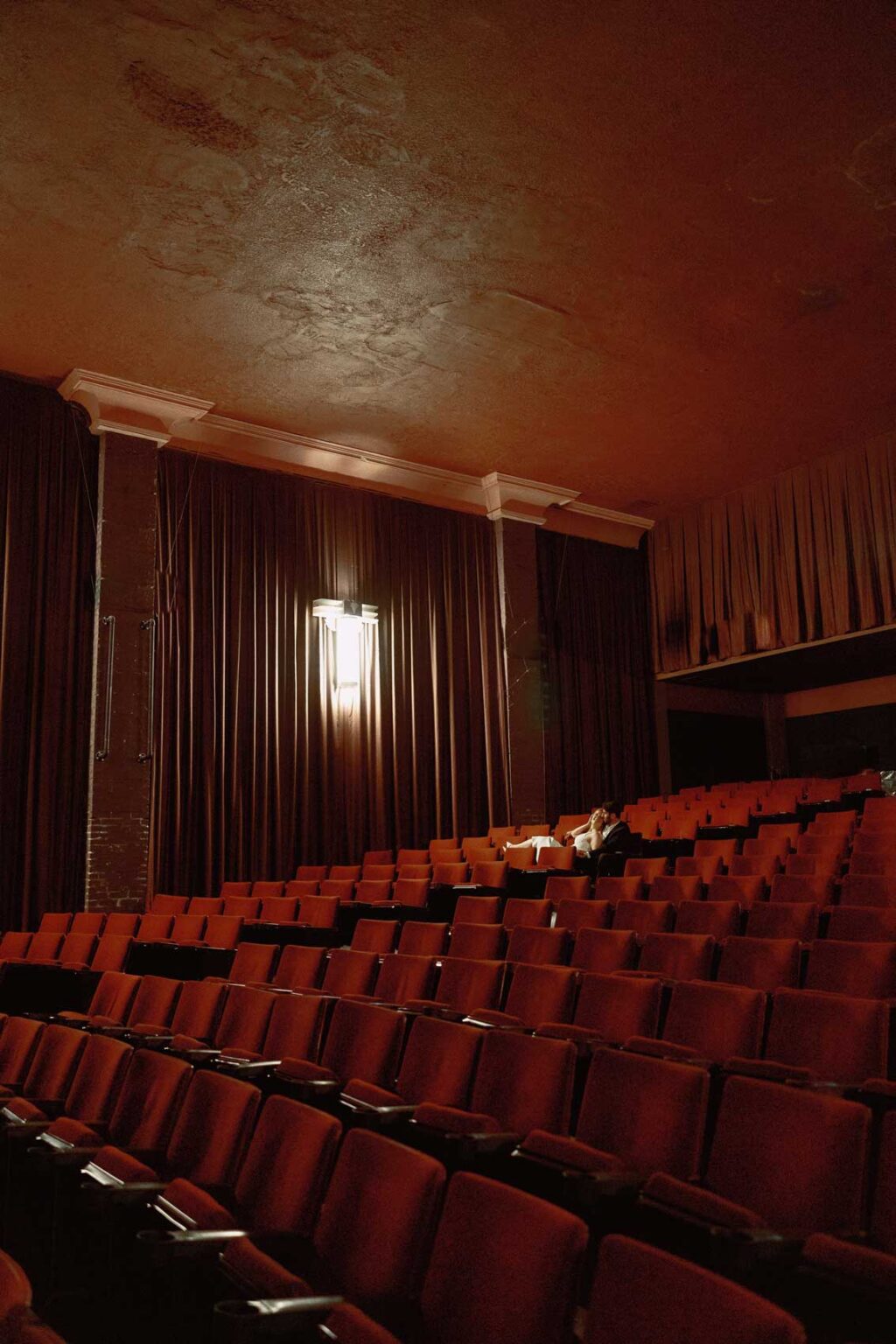 Engaged couple sitting together under the glow of theater lights at SIFF Cinema, Seattle engagement photographer