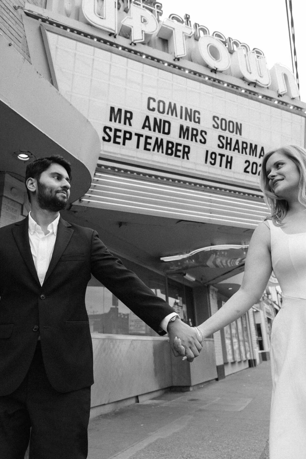 Couple standing beneath a lit movie theater marquee sign with their wedding date, SIFF Cinema Uptown Seattle